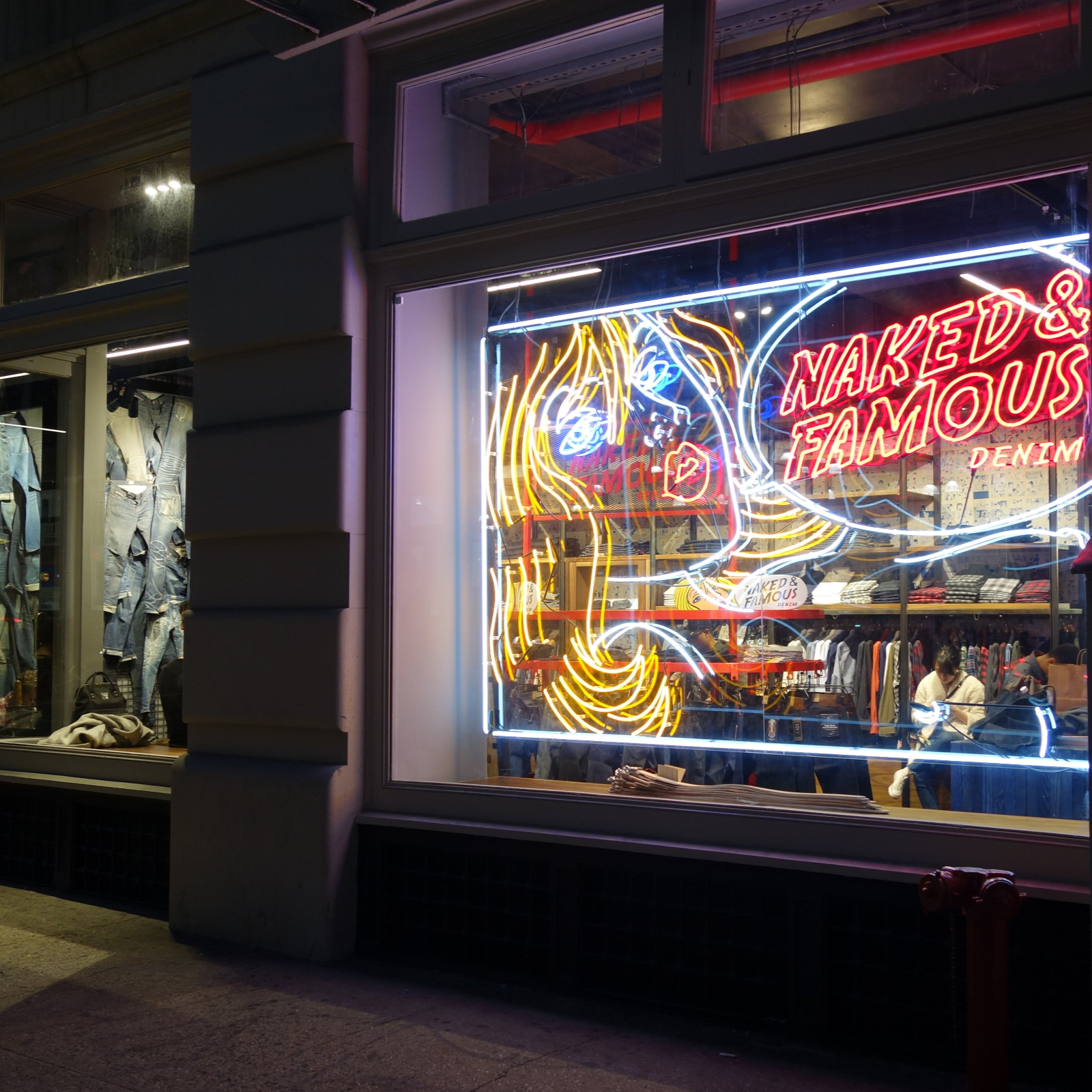 Neon sign for 'Naked & Famous Denim' in a store window.